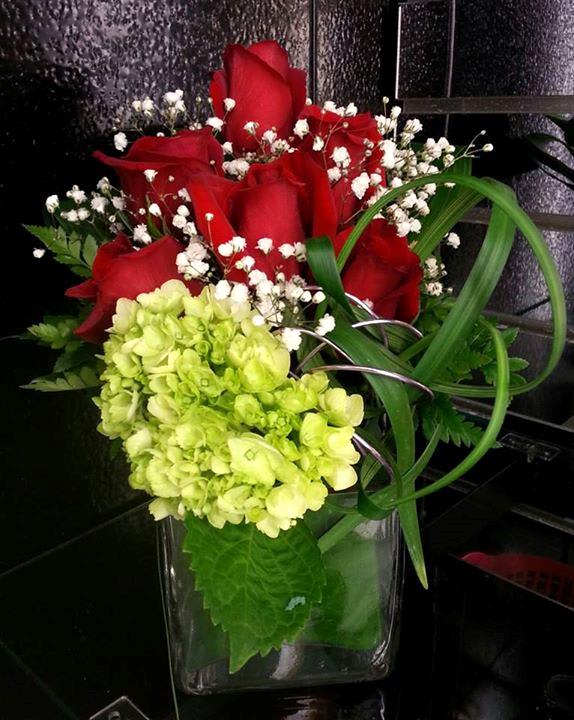 Red roses and green hydrangea in a clear glass vase
