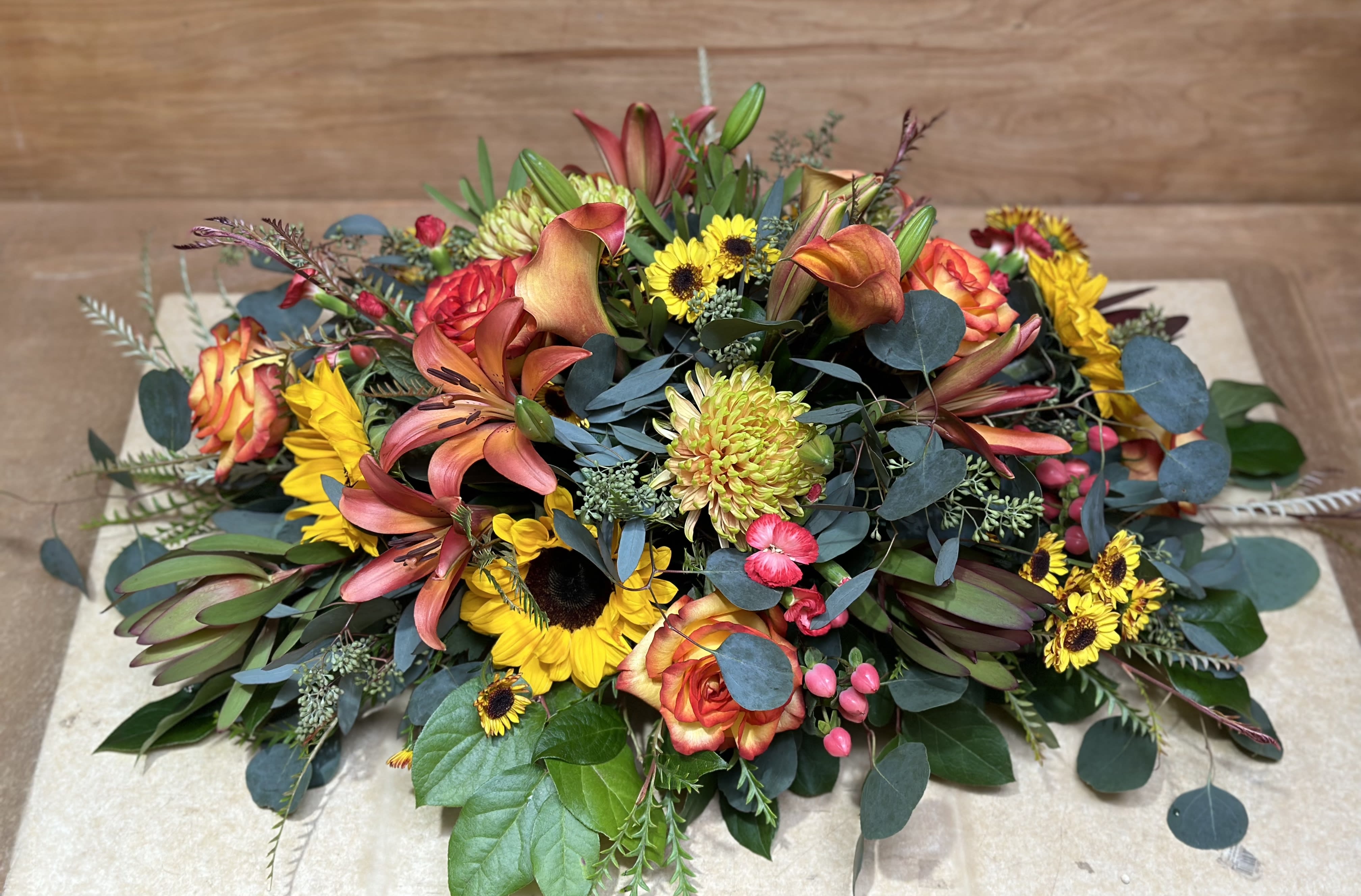 Low floral centerpiece with orange lilies, roses, and yellow sunflowers