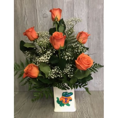 Orange roses arranged in a white vase with baby's breath