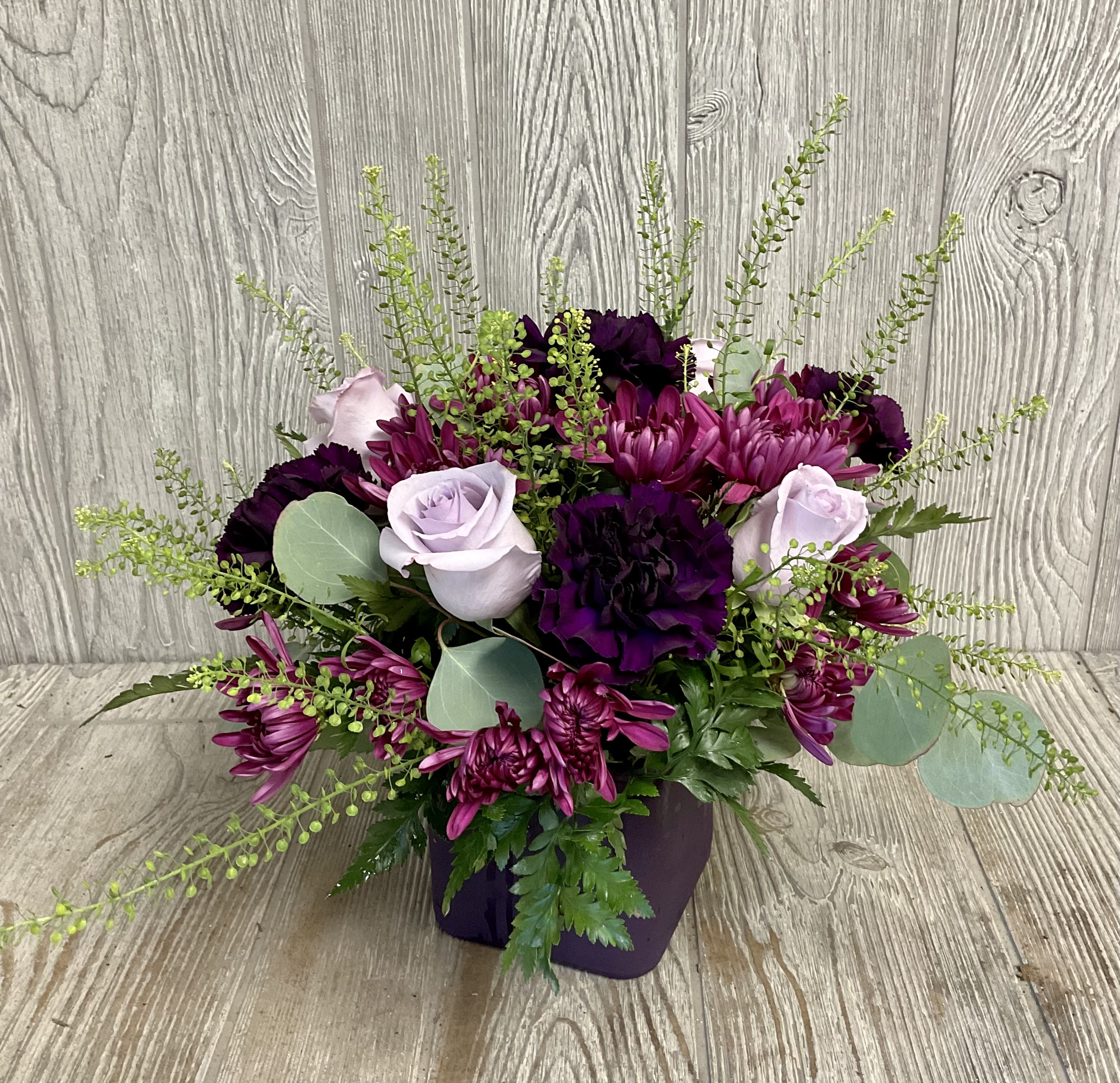 Purple and lavender floral arrangement in a dark vase