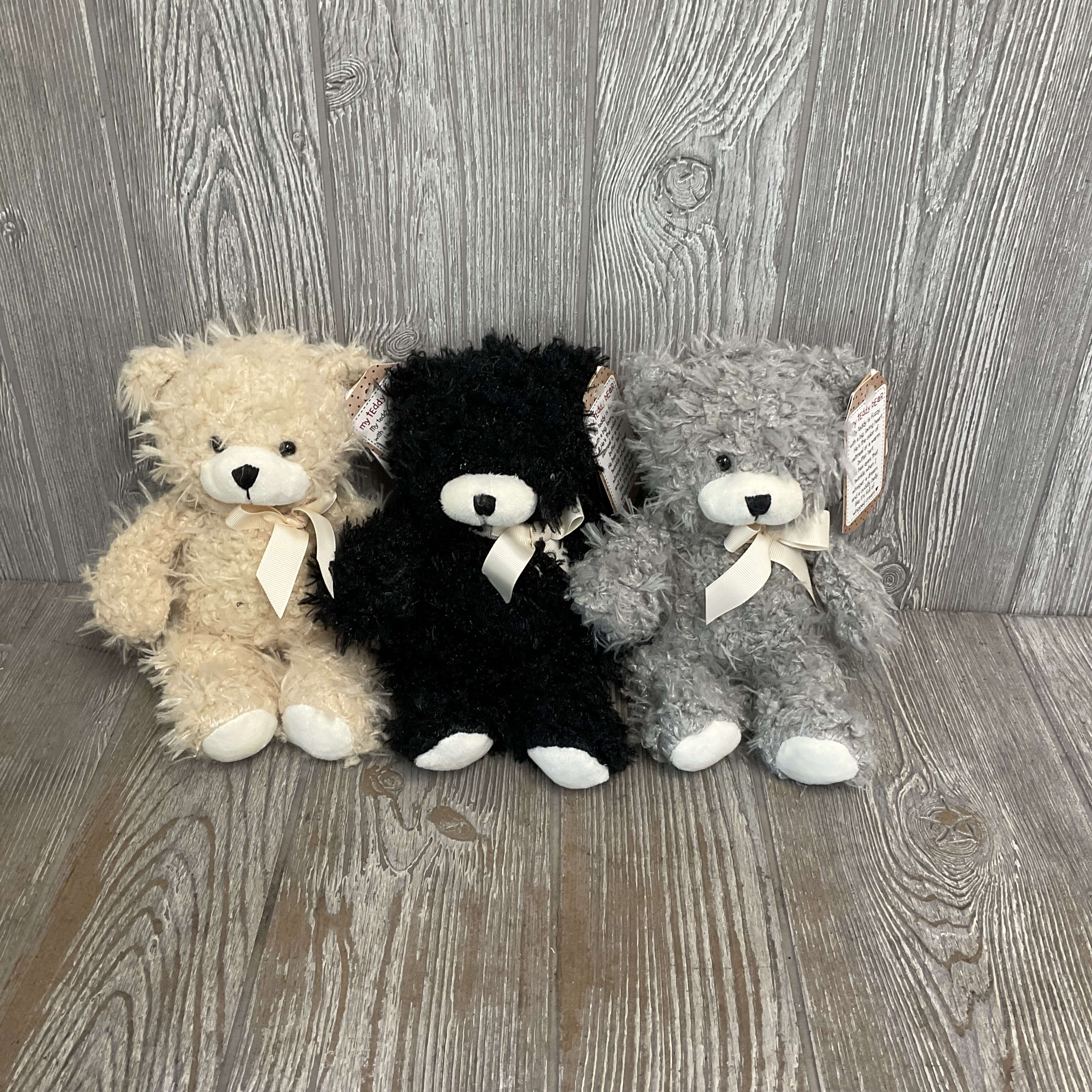Three teddy bears in beige, black, and gray with ribbon bows