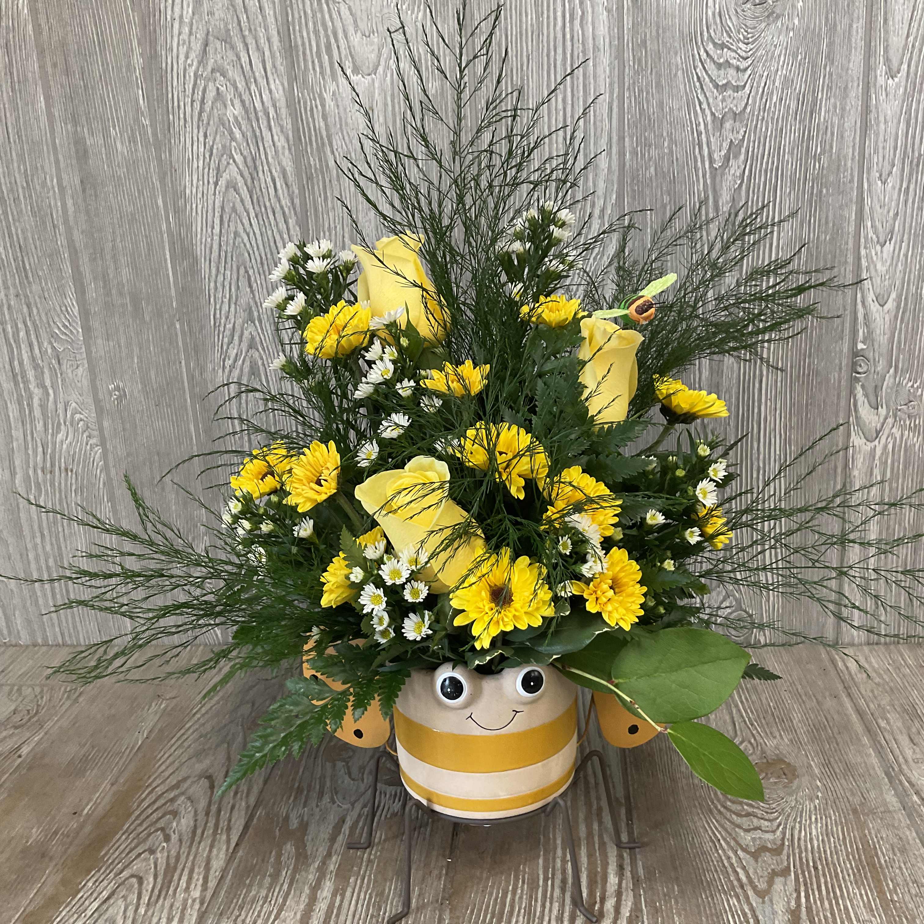 Yellow and white flower arrangement in a striped smiling pot