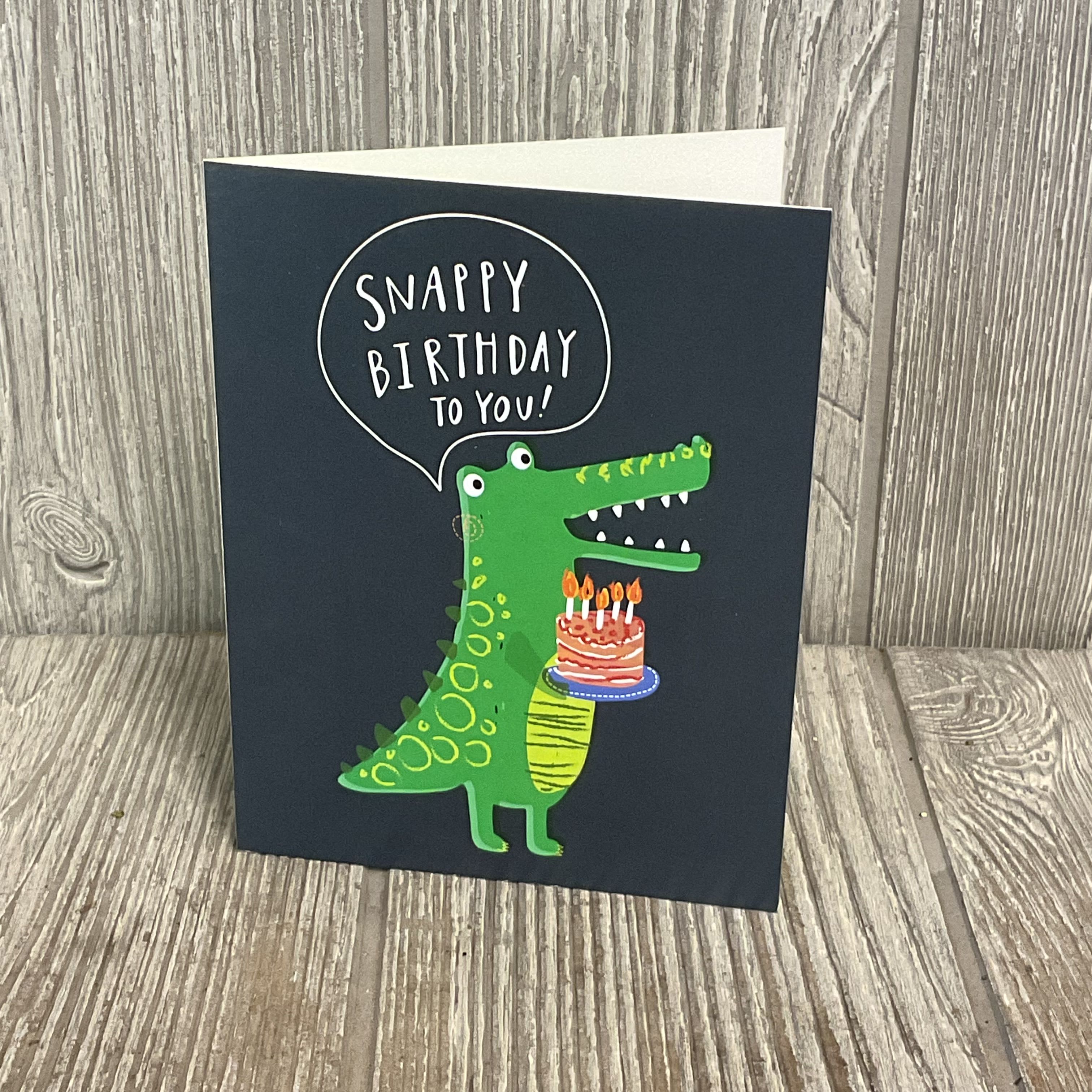 Birthday card with a green cartoon crocodile holding a cake