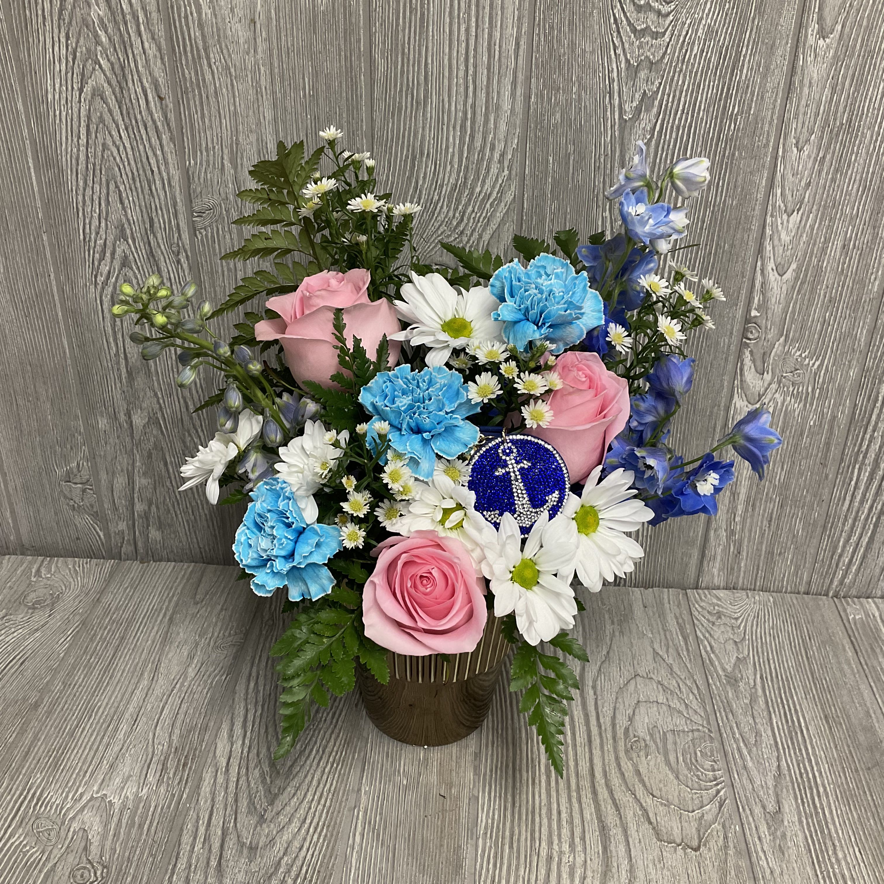 Pink roses and blue carnations in a vase with white daisies.