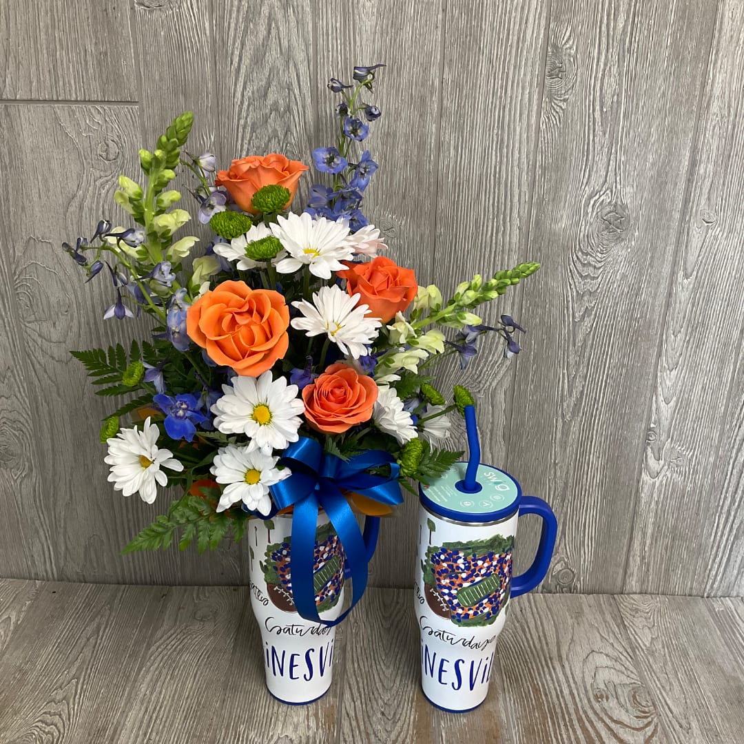 Orange roses and white daisies in a tall travel tumbler with a blue ribbon.