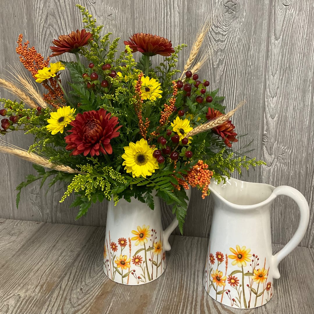 Autumn bouquet of red and yellow daisies in a white floral pitcher