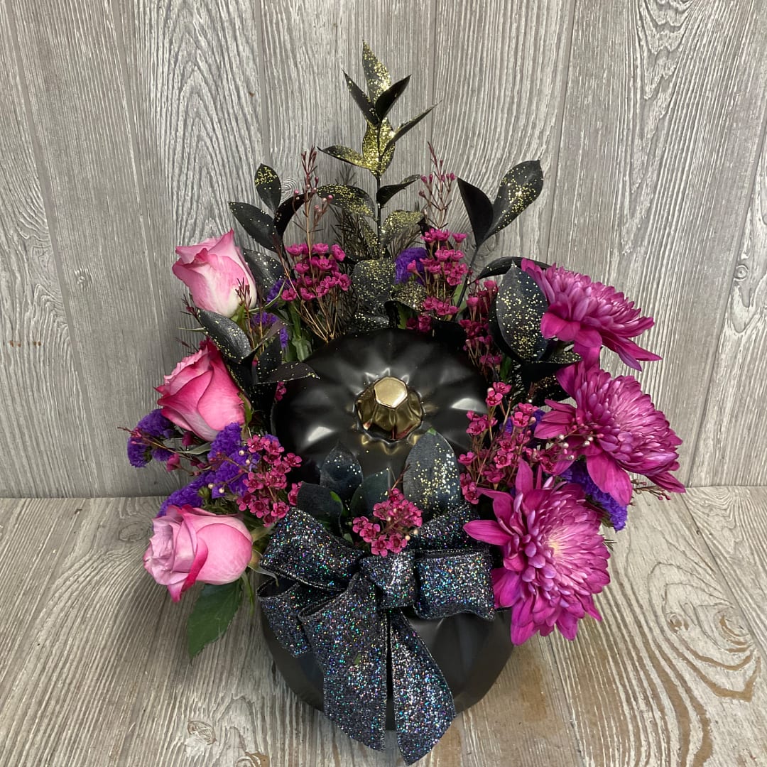 Pink roses and purple mums arranged in a black container with a glittery bow