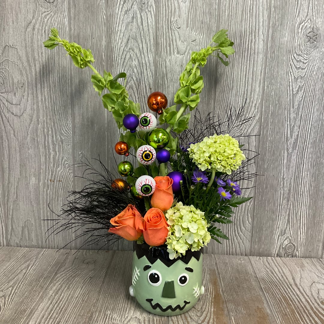 Halloween bouquet in a Frankenstein face vase with orange roses and eyeball picks