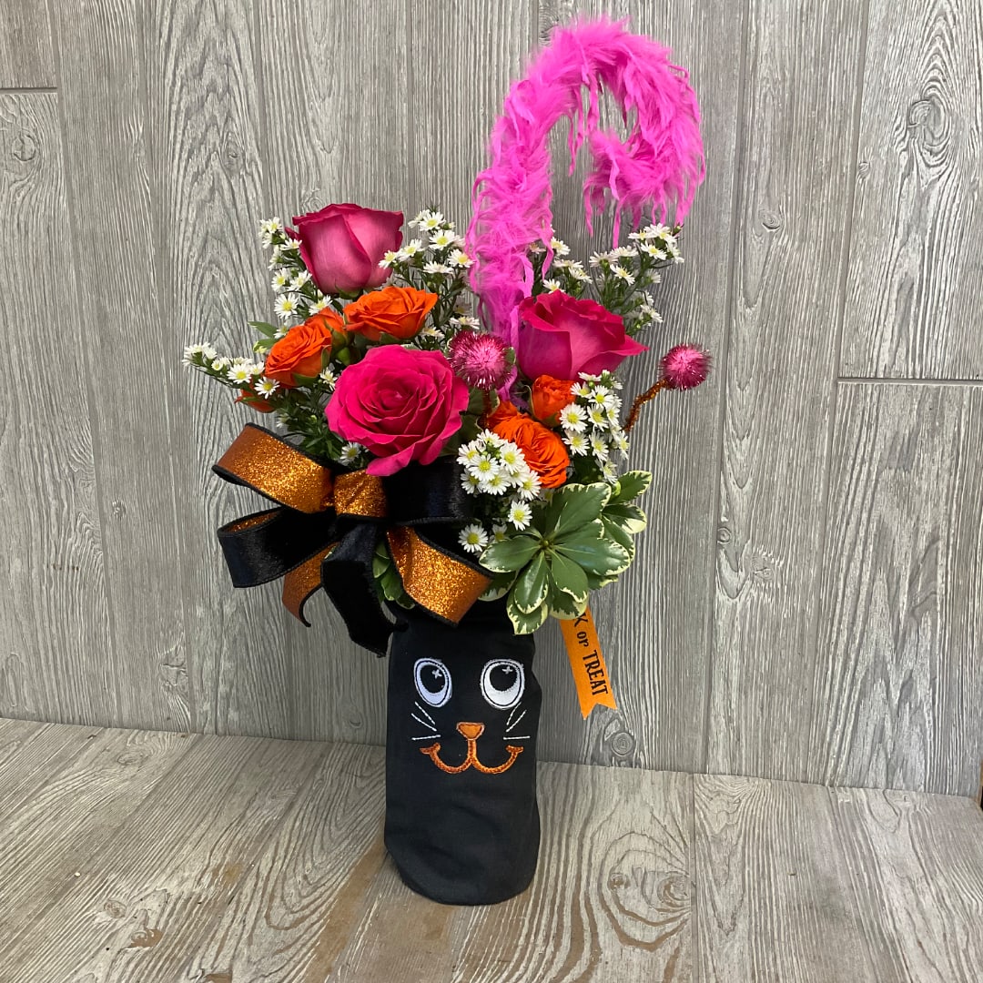 Bright mixed flower arrangement in a black cat-themed container with a pink feather topper