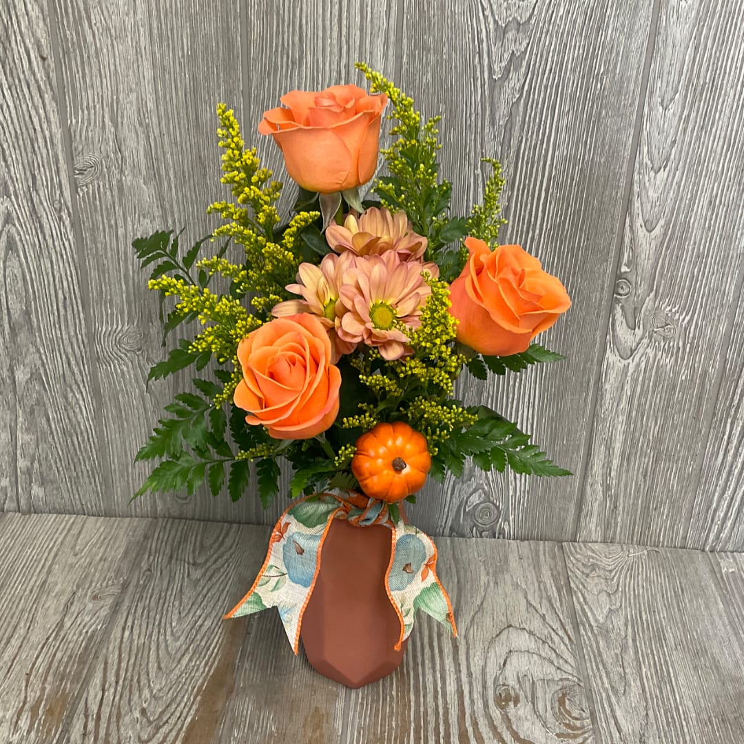 Orange roses and daisies in a small vase with a ribbon bow
