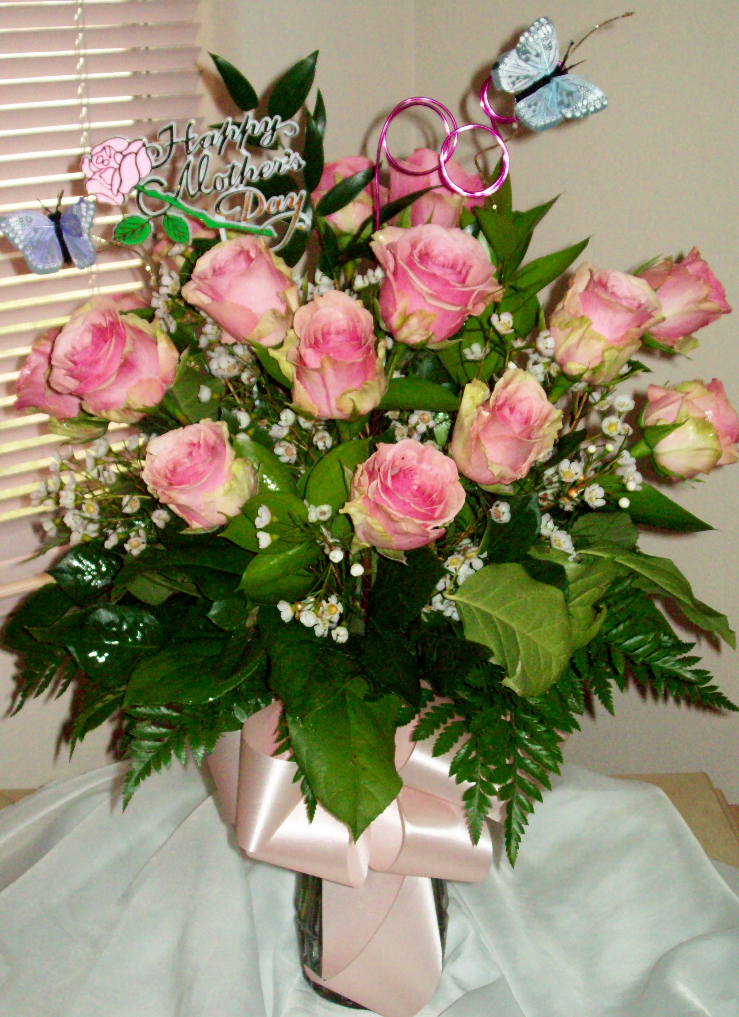 Pink roses arranged in a vase with a Mother's Day topper and butterfly picks