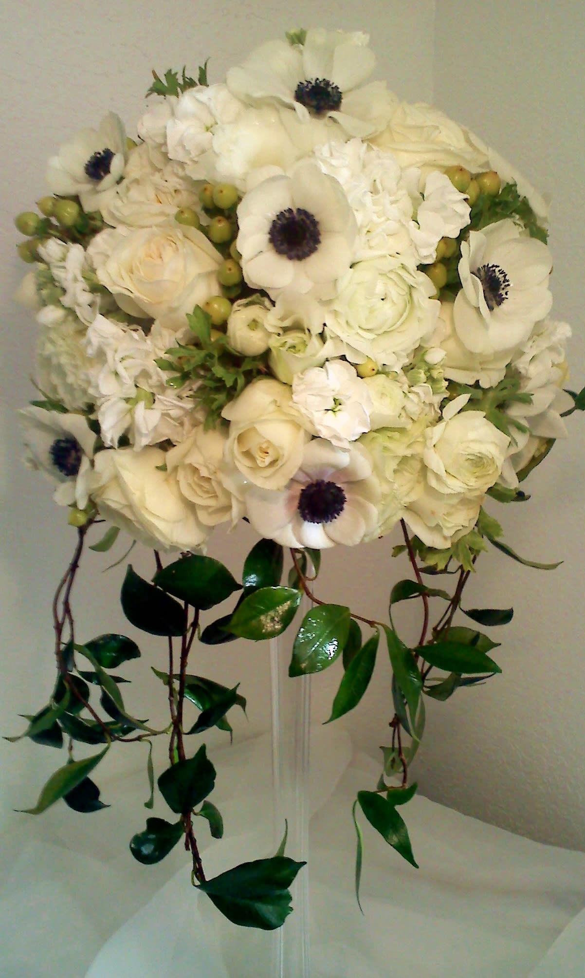 White bridal bouquet with roses and anemones, trailing greenery