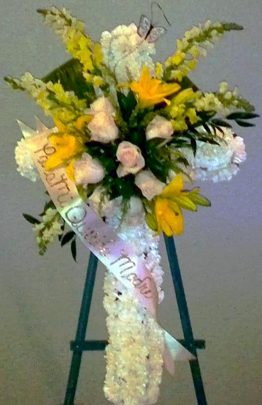 Standing floral spray with yellow and white flowers on an easel