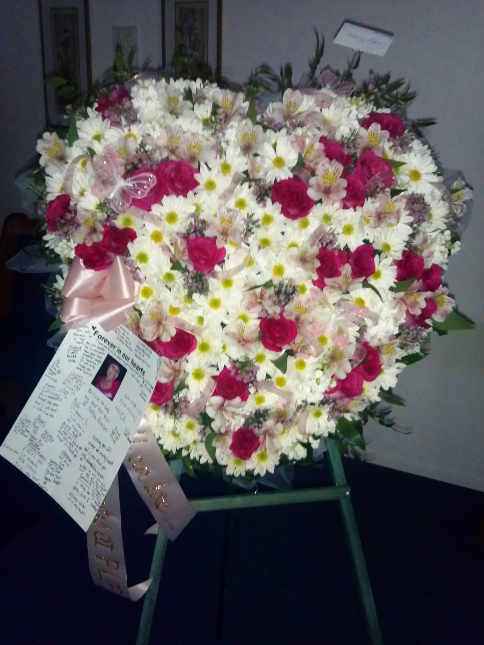Heart-shaped floral spray with white daisies and pink roses on an easel