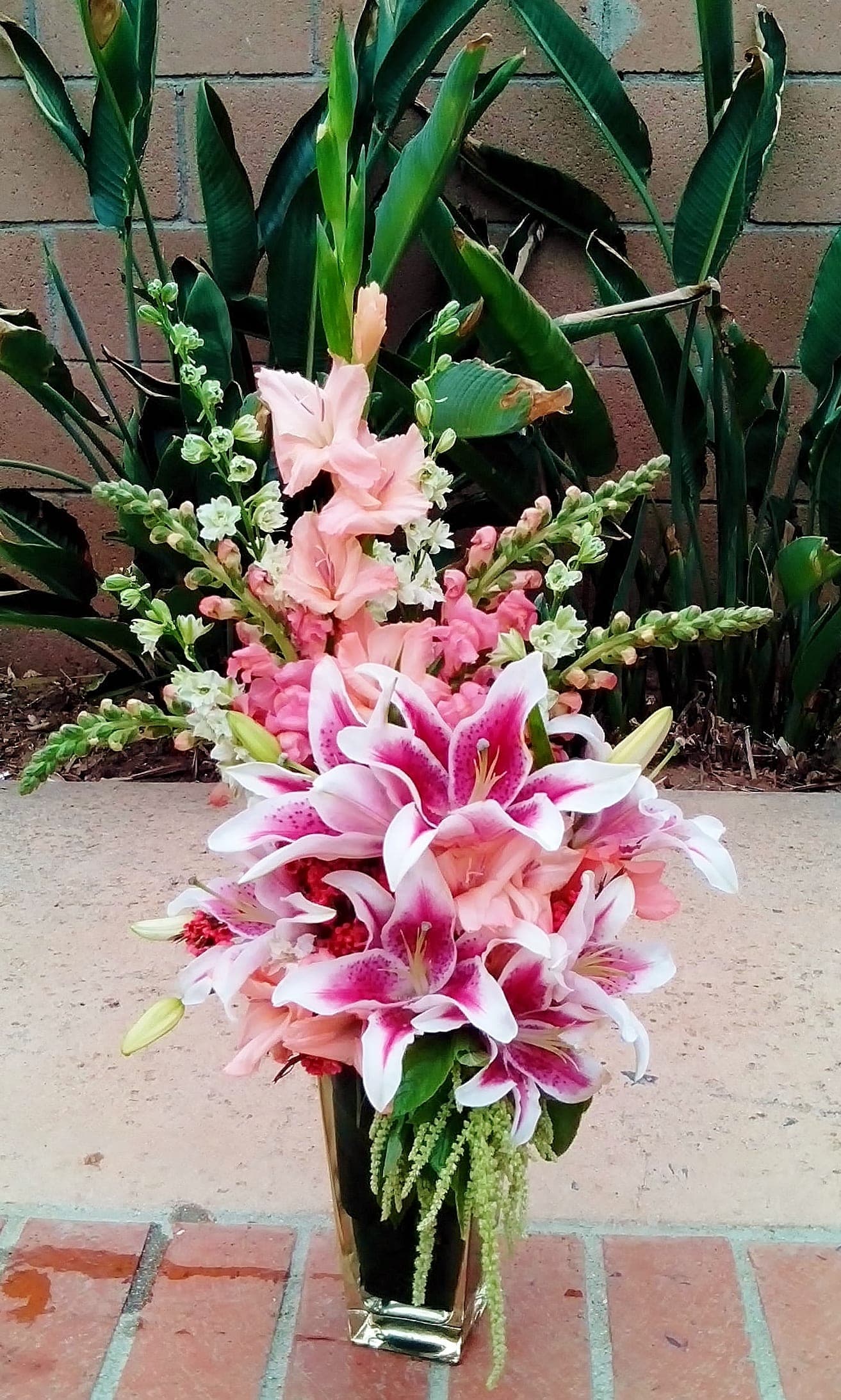 Pink and white lilies arranged in a tall gold vase
