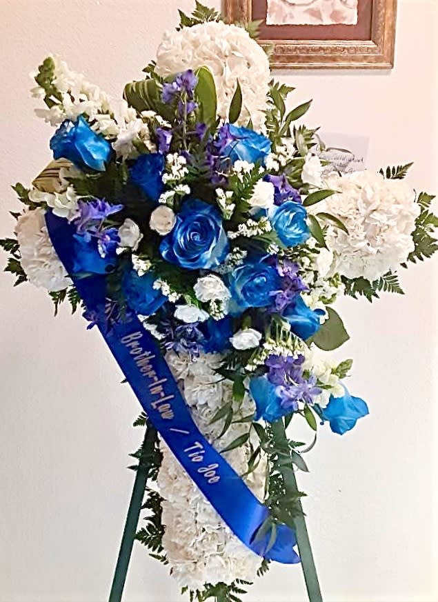 Blue and white funeral spray with roses and hydrangeas on a stand