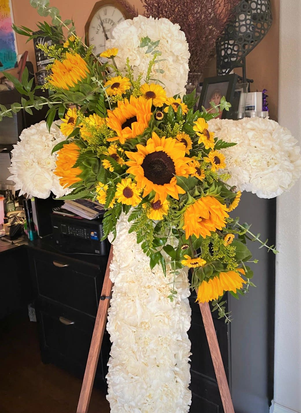 White floral cross with yellow sunflowers on an easel