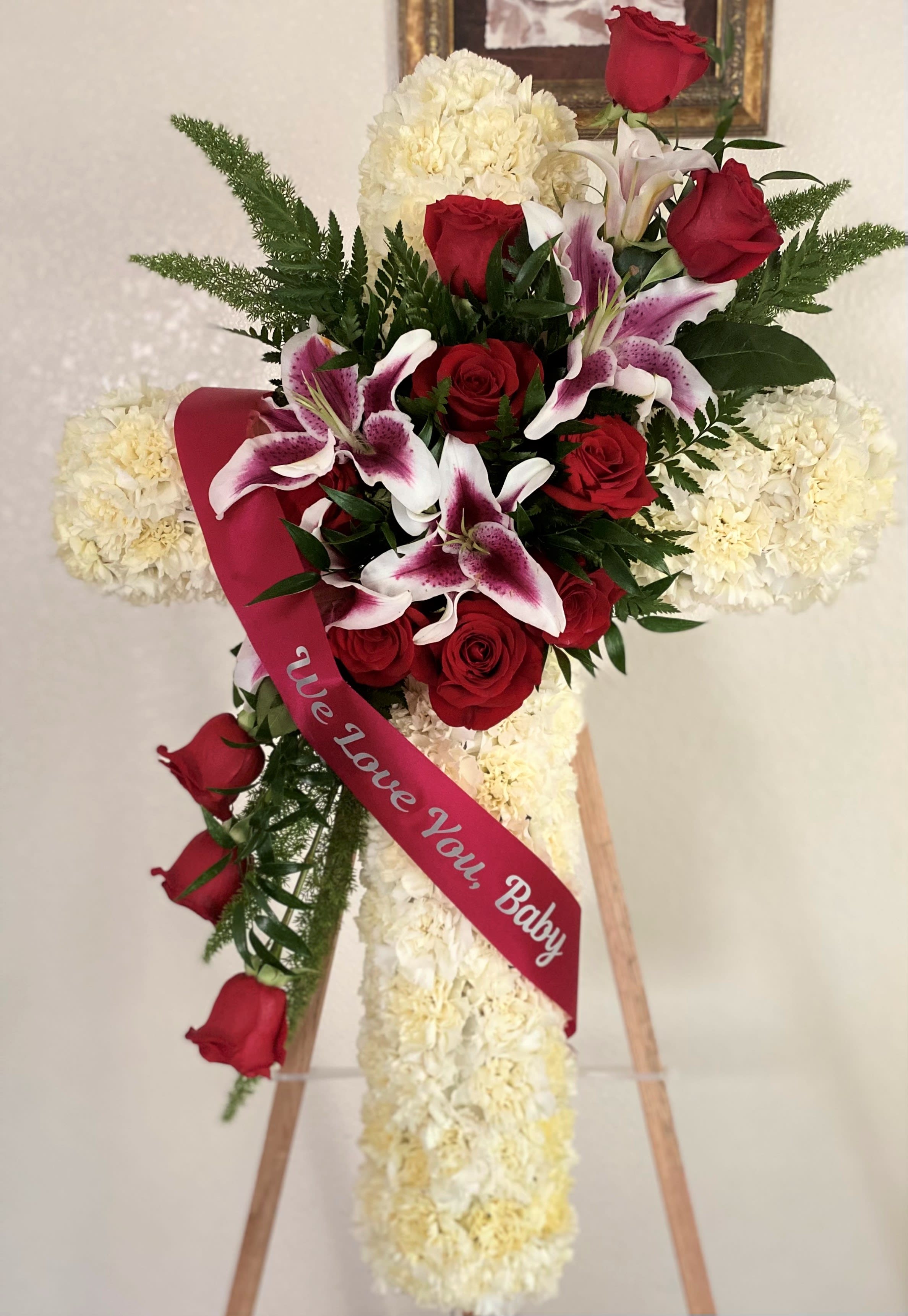 Standing floral cross with red roses and white lilies on an easel