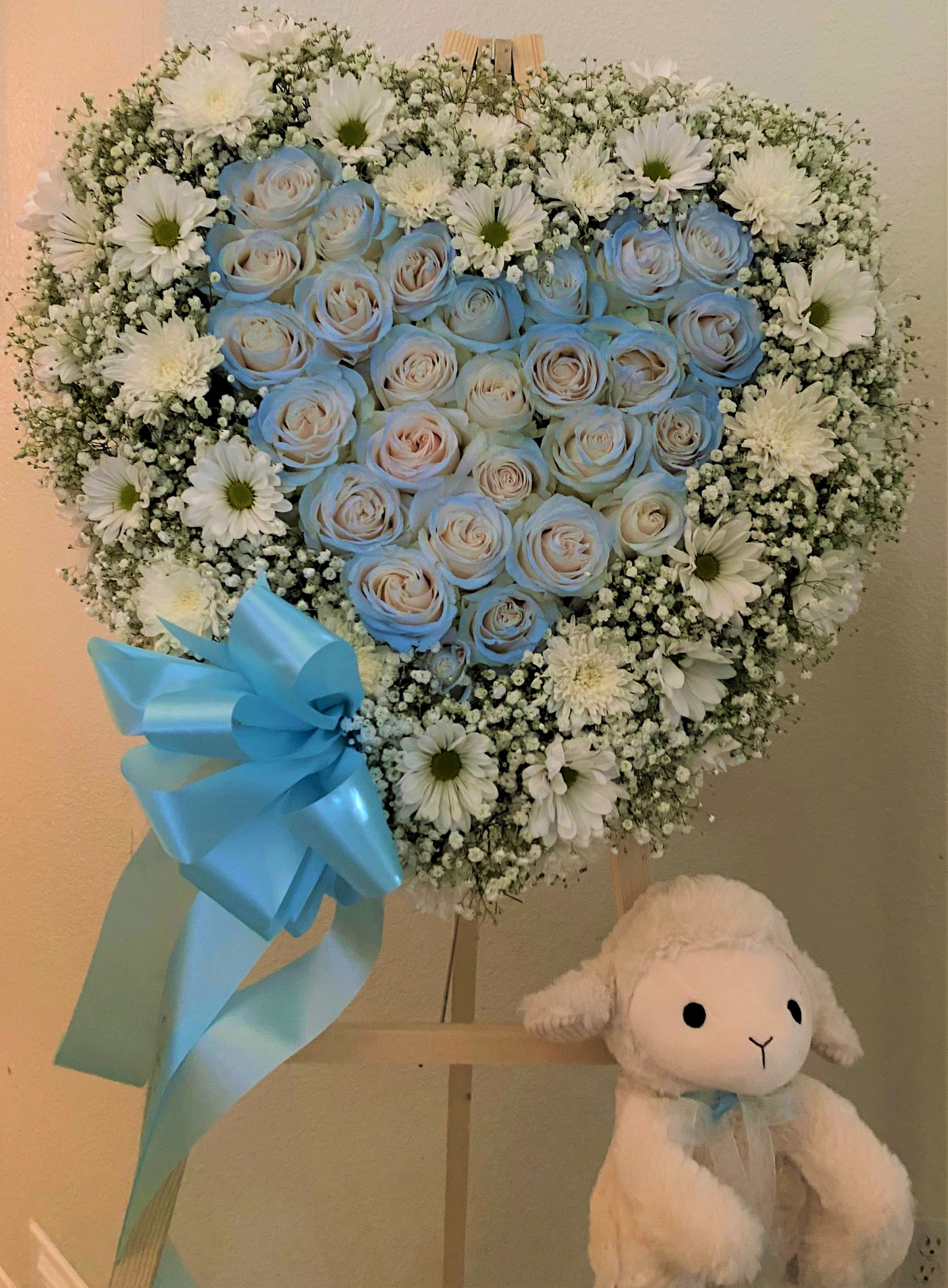 Heart-shaped bouquet of blue roses and white daisies with a blue ribbon
