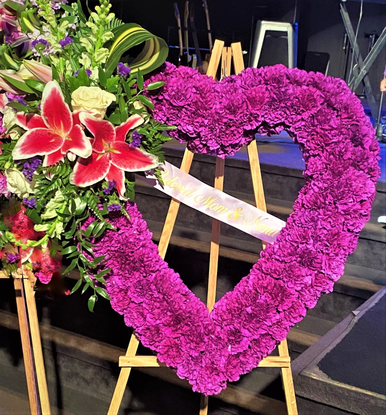 Heart-shaped floral tribute on an easel with pink flowers and lilies
