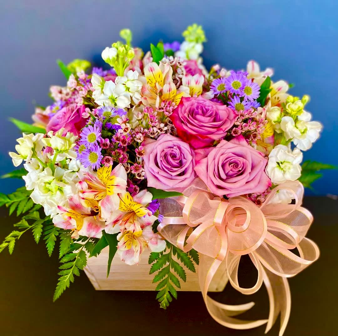 Pink and lavender rose bouquet in a wooden box with a ribbon bow