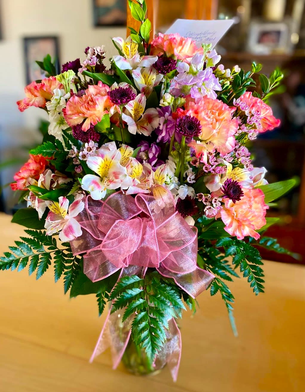 Mixed pink and white bouquet in a glass vase with a pink ribbon