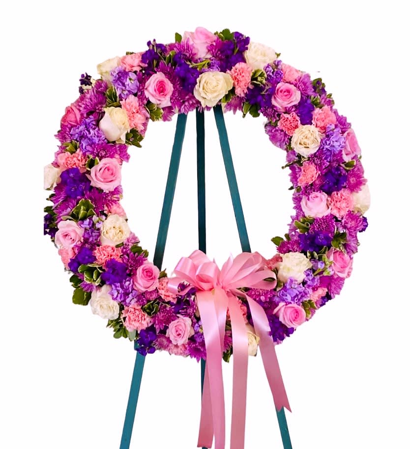Circular floral wreath on an easel with pink, purple, and white flowers