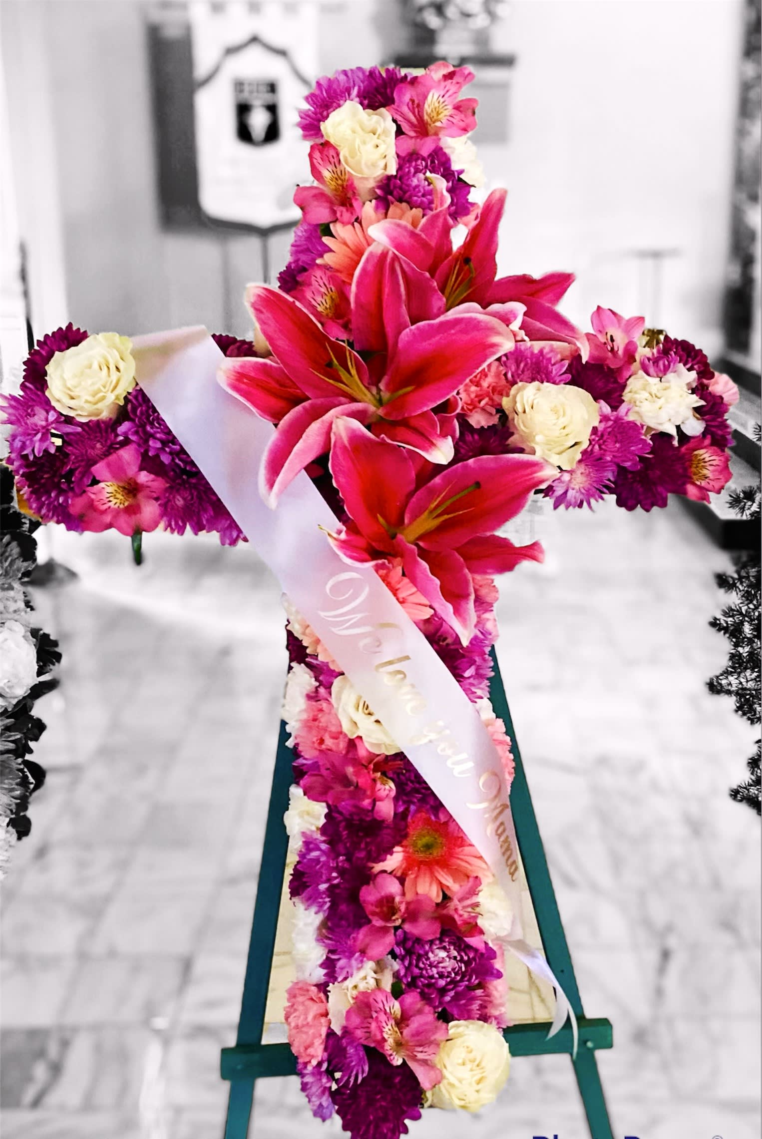 Pink and white floral standing arrangement on an easel with a ribbon sash