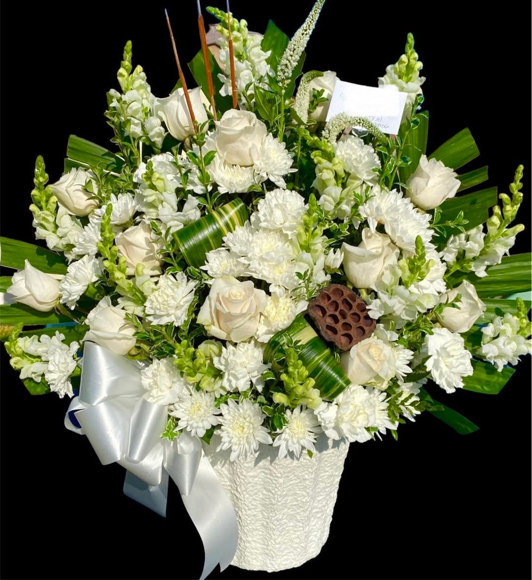 White roses and chrysanthemums in a white basket with a silver ribbon