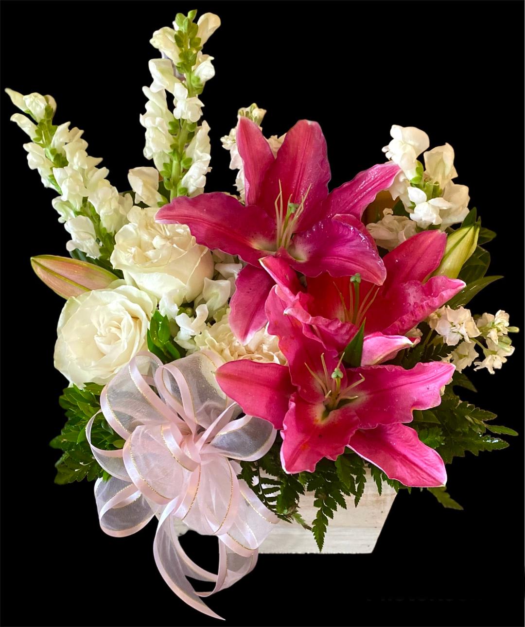 Pink lilies and white roses in a white container with a ribbon bow