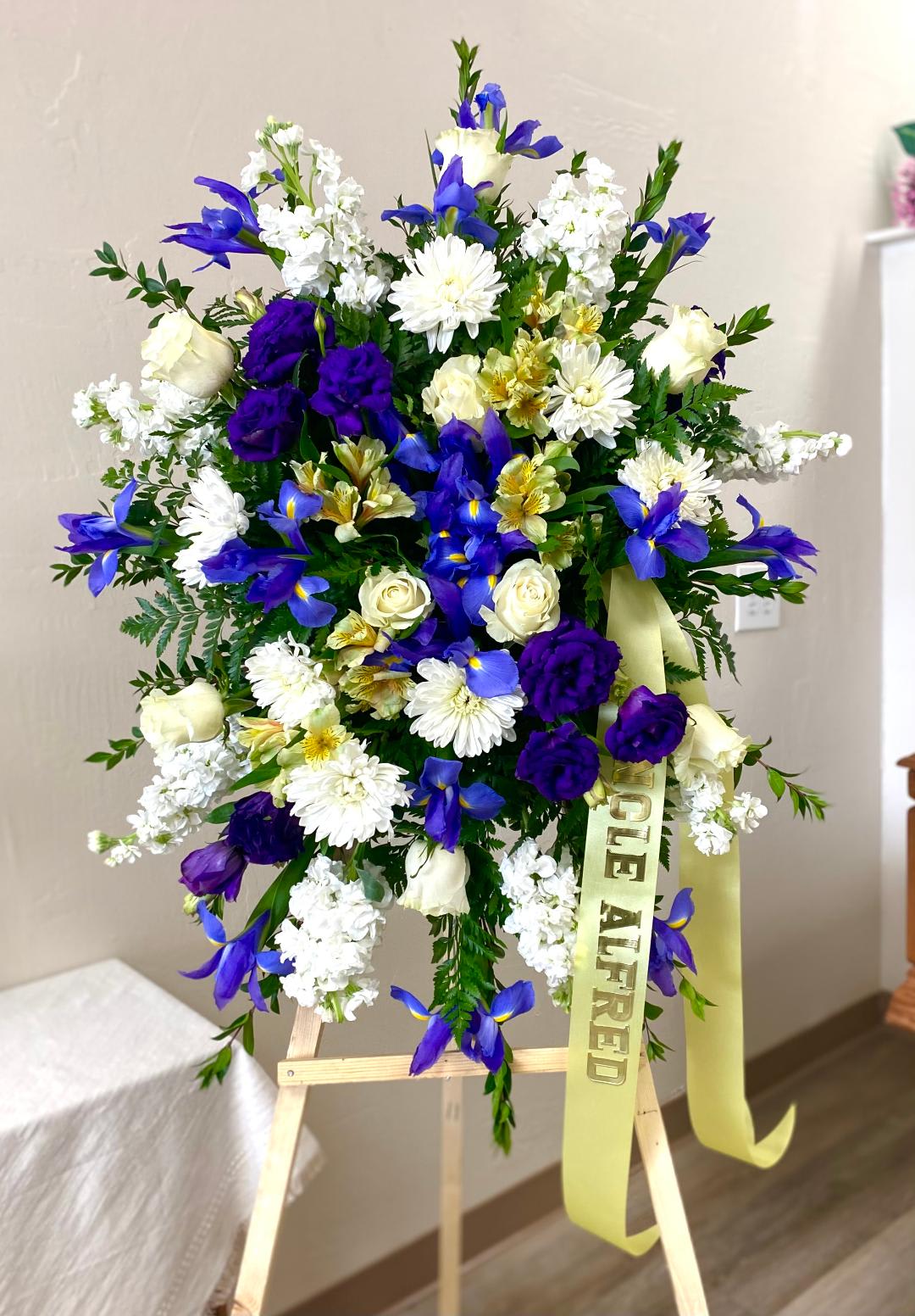 Standing floral spray with blue, white, and purple flowers on an easel