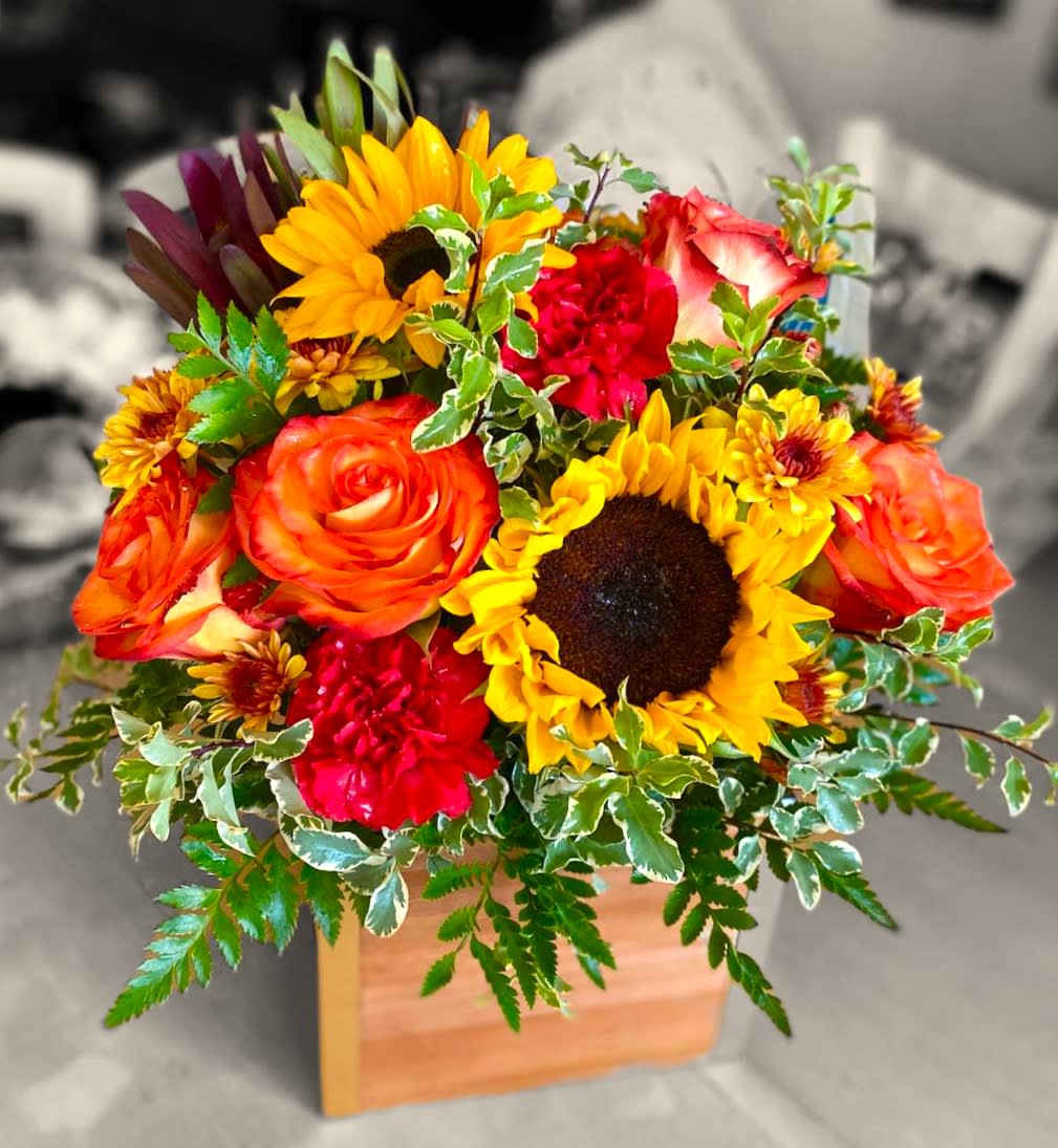 Bright mixed bouquet with sunflowers, roses, and carnations in a wooden box
