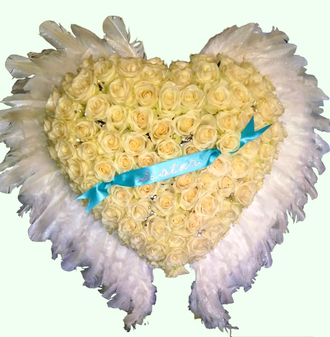 Heart-shaped bouquet of cream roses with white feather trim and a blue ribbon