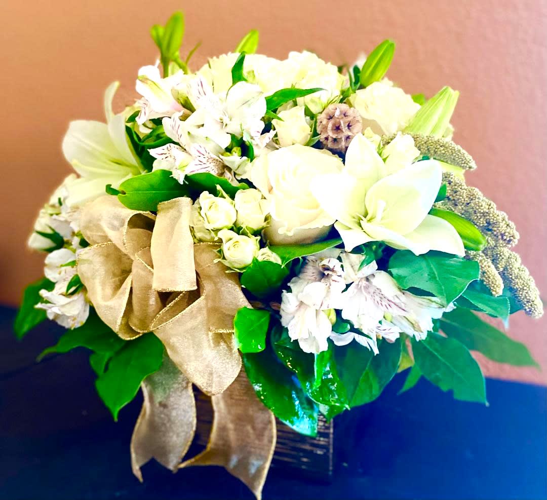 White floral arrangement with a gold ribbon in a dark vase