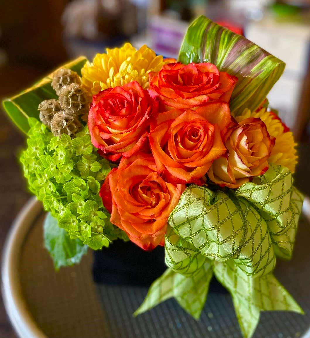 Bouquet of orange roses and yellow mums with a green ribbon bow