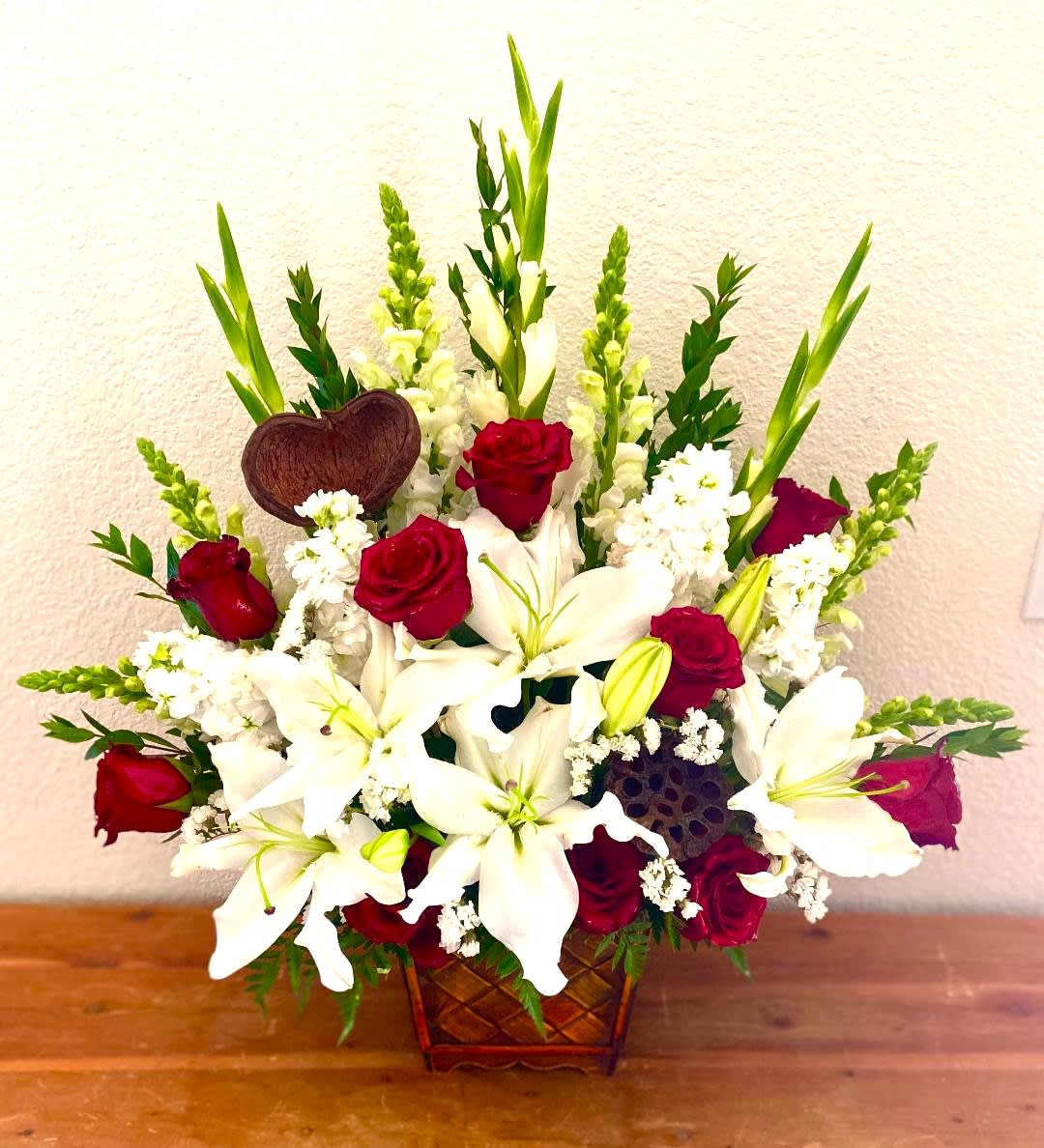 Red roses and white lilies in a woven basket arrangement