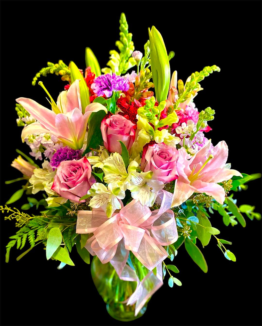 Pink roses and lilies in a glass vase with a pink ribbon