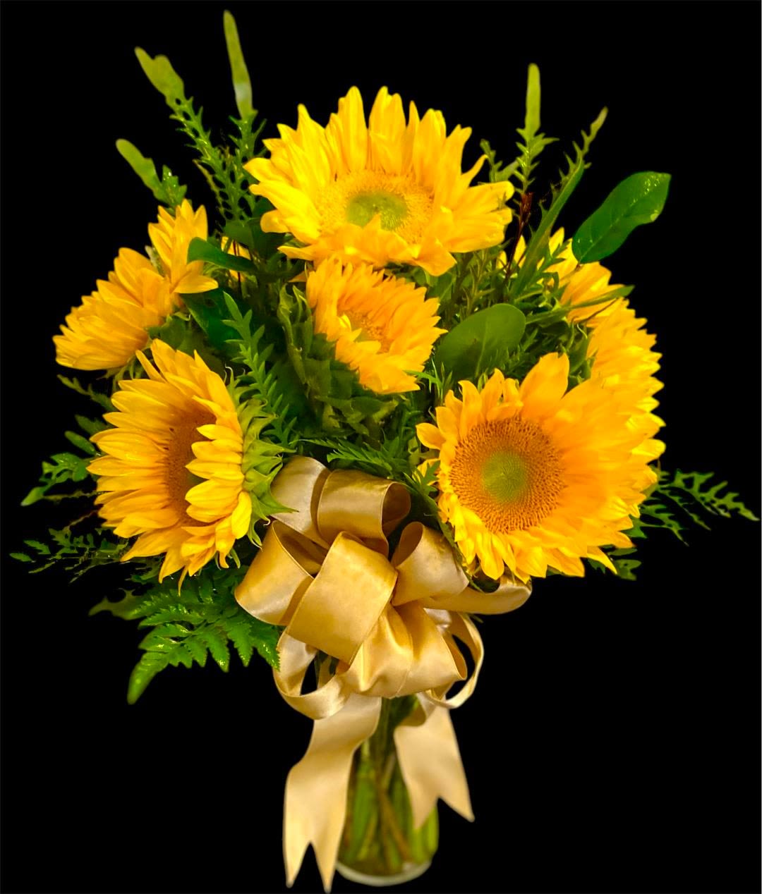 Bouquet of yellow sunflowers with a gold ribbon in a glass vase