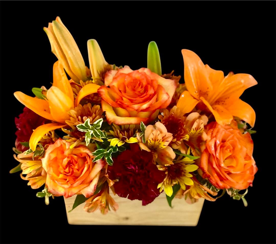 Orange roses and lilies arranged in a rectangular wooden container