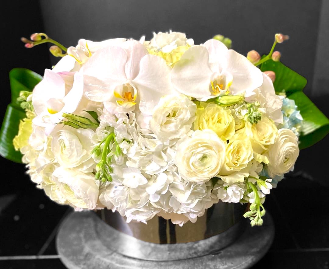 White and pale yellow bouquet with orchids and roses in a vase