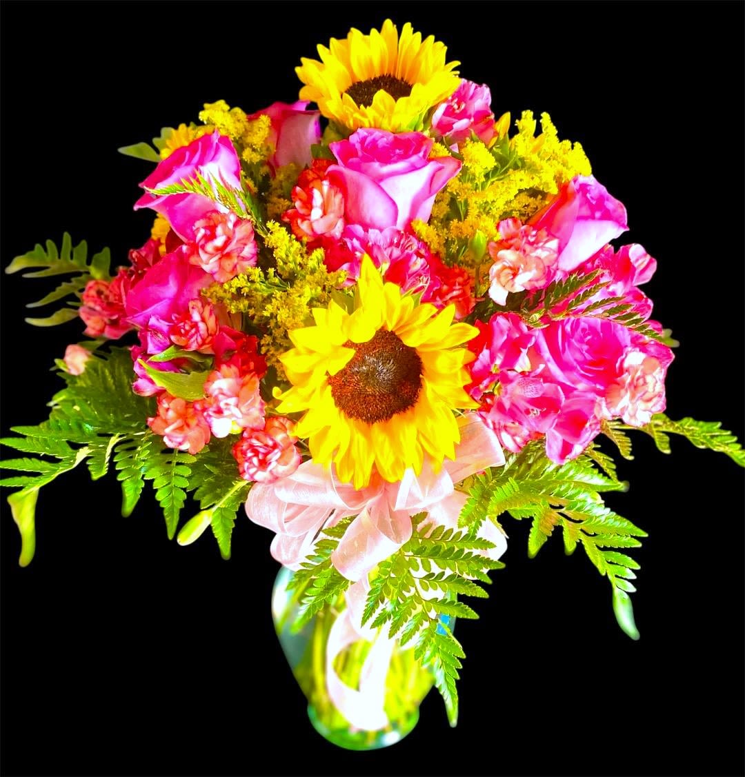 Bouquet of pink roses and yellow sunflowers in a glass vase