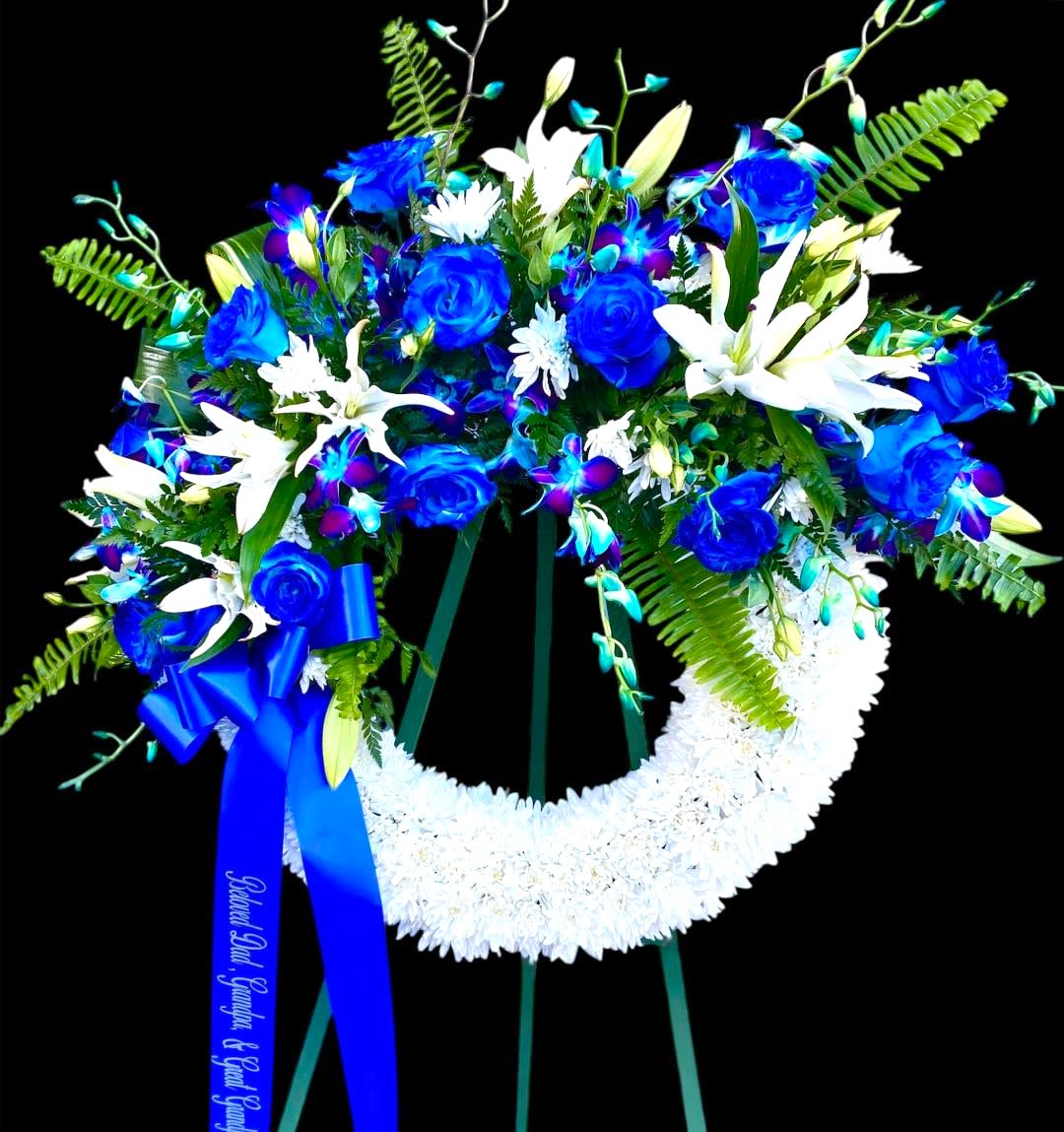 Blue and white funeral wreath on a stand with a ribbon