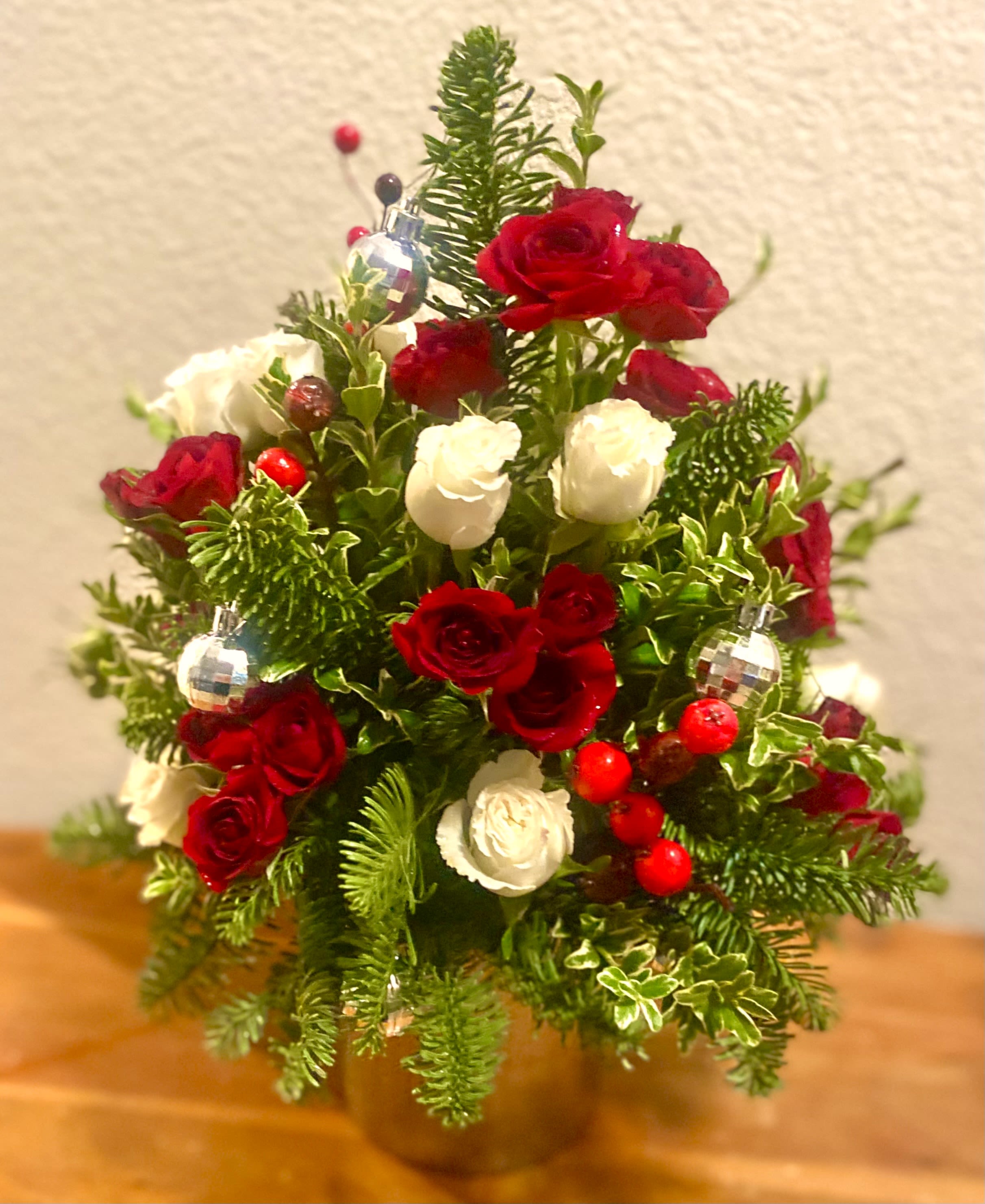 Red and white rose arrangement with holiday ornaments in a vase