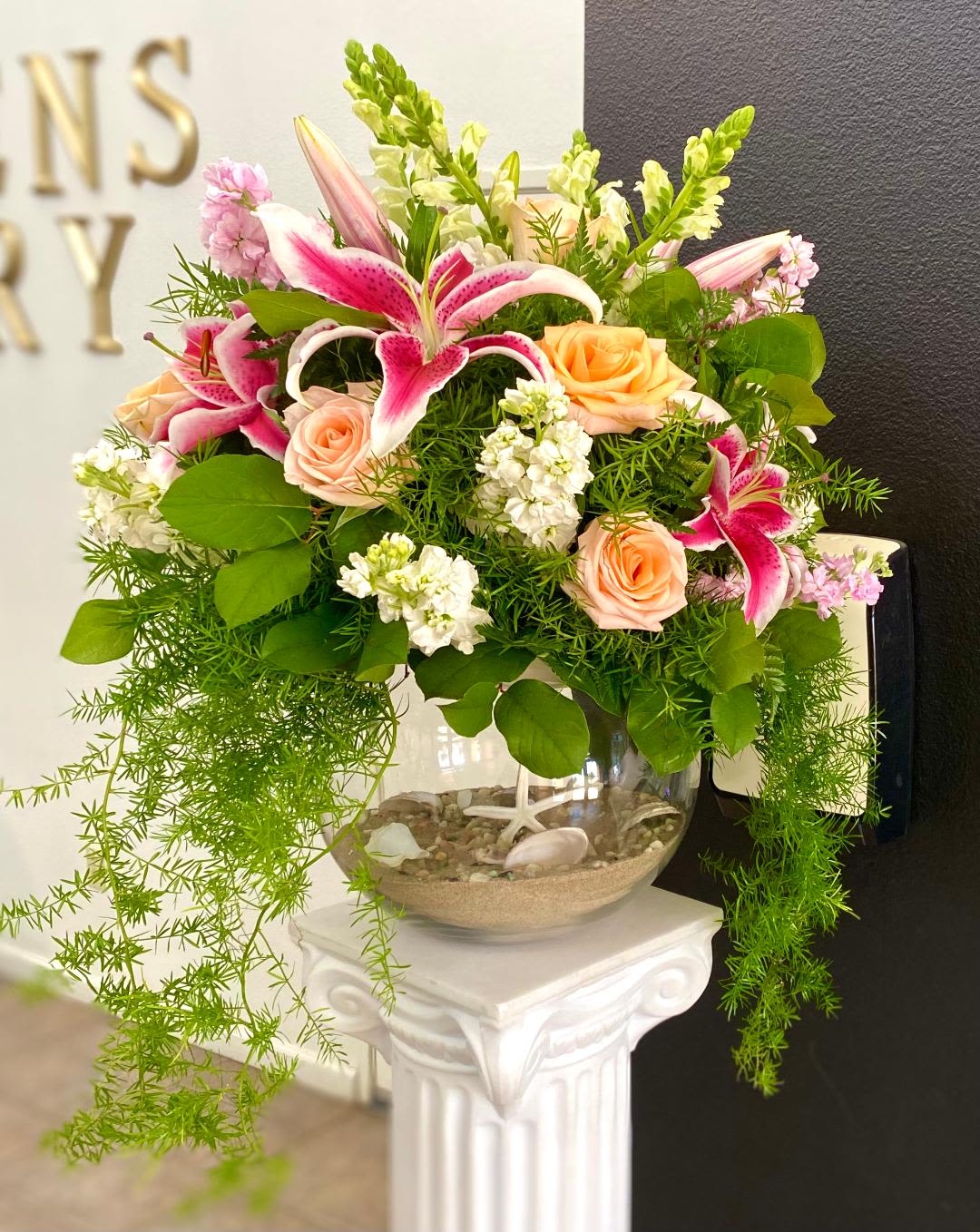 Pink lilies and peach roses arranged in a glass bowl vase