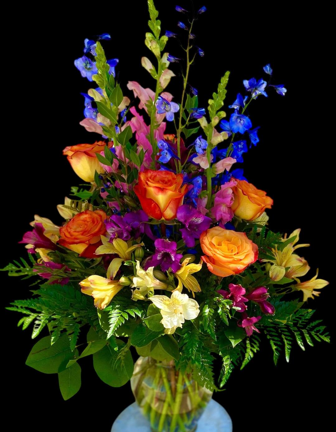 Colorful bouquet of roses, snapdragons, and alstroemeria in a glass vase