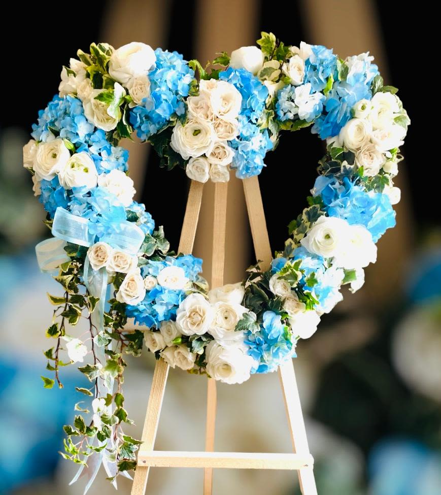 Heart-shaped floral wreath of white and blue flowers on an easel