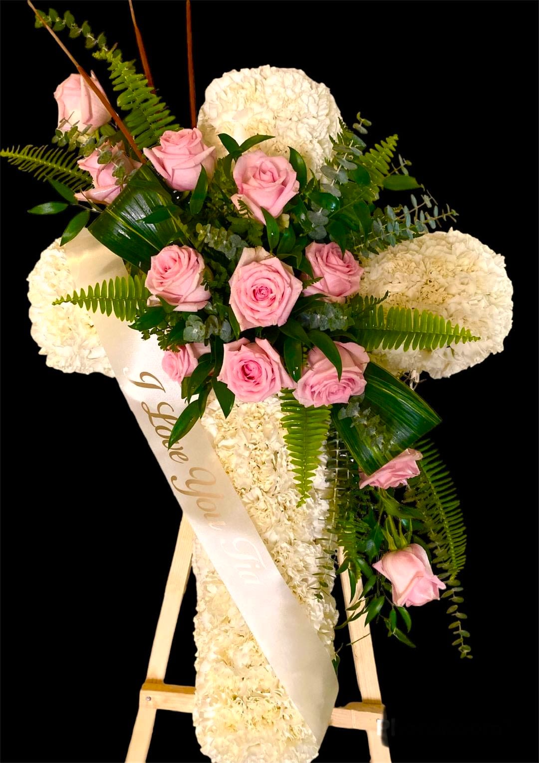 Pink roses and white flowers arranged on a standing easel with a sash