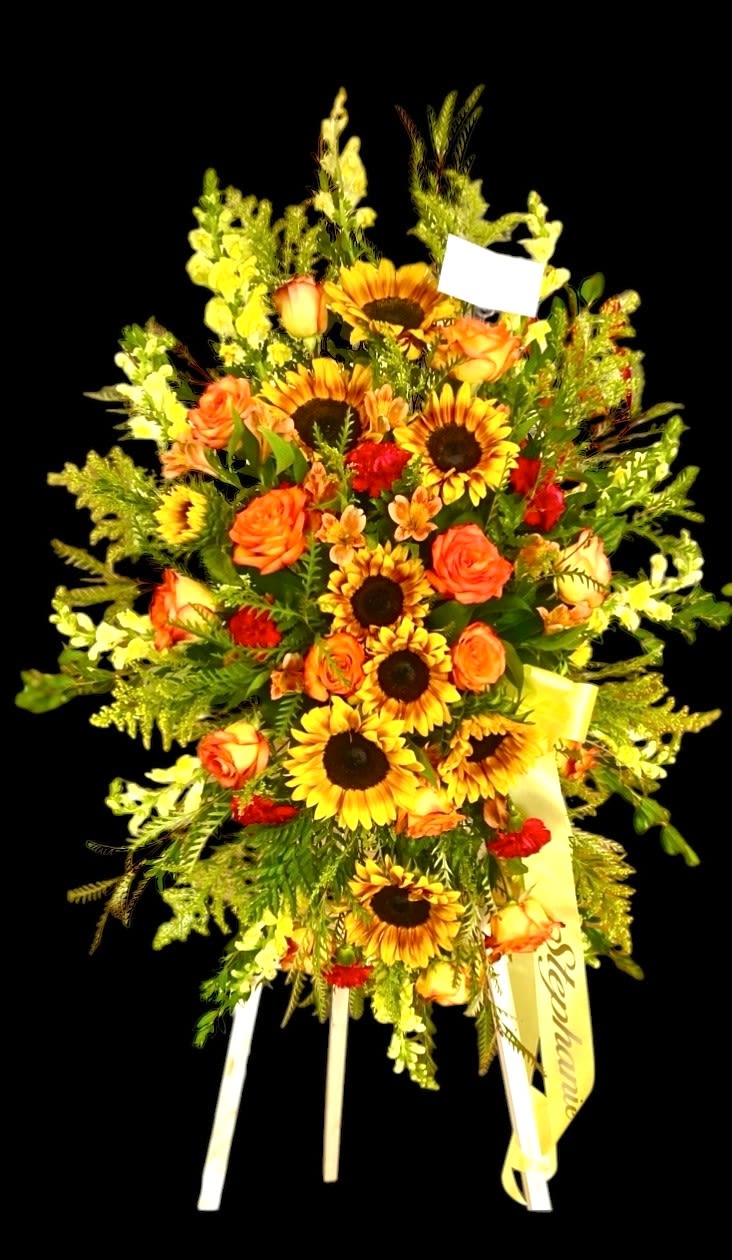 Tall floral standing spray with sunflowers and orange roses on a black background