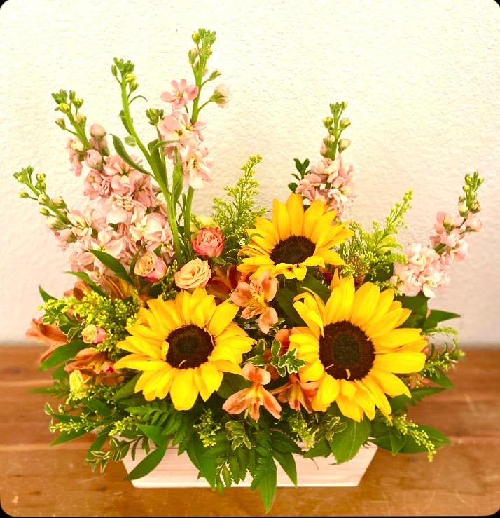 Sunflower and pink mixed flower arrangement in a white container