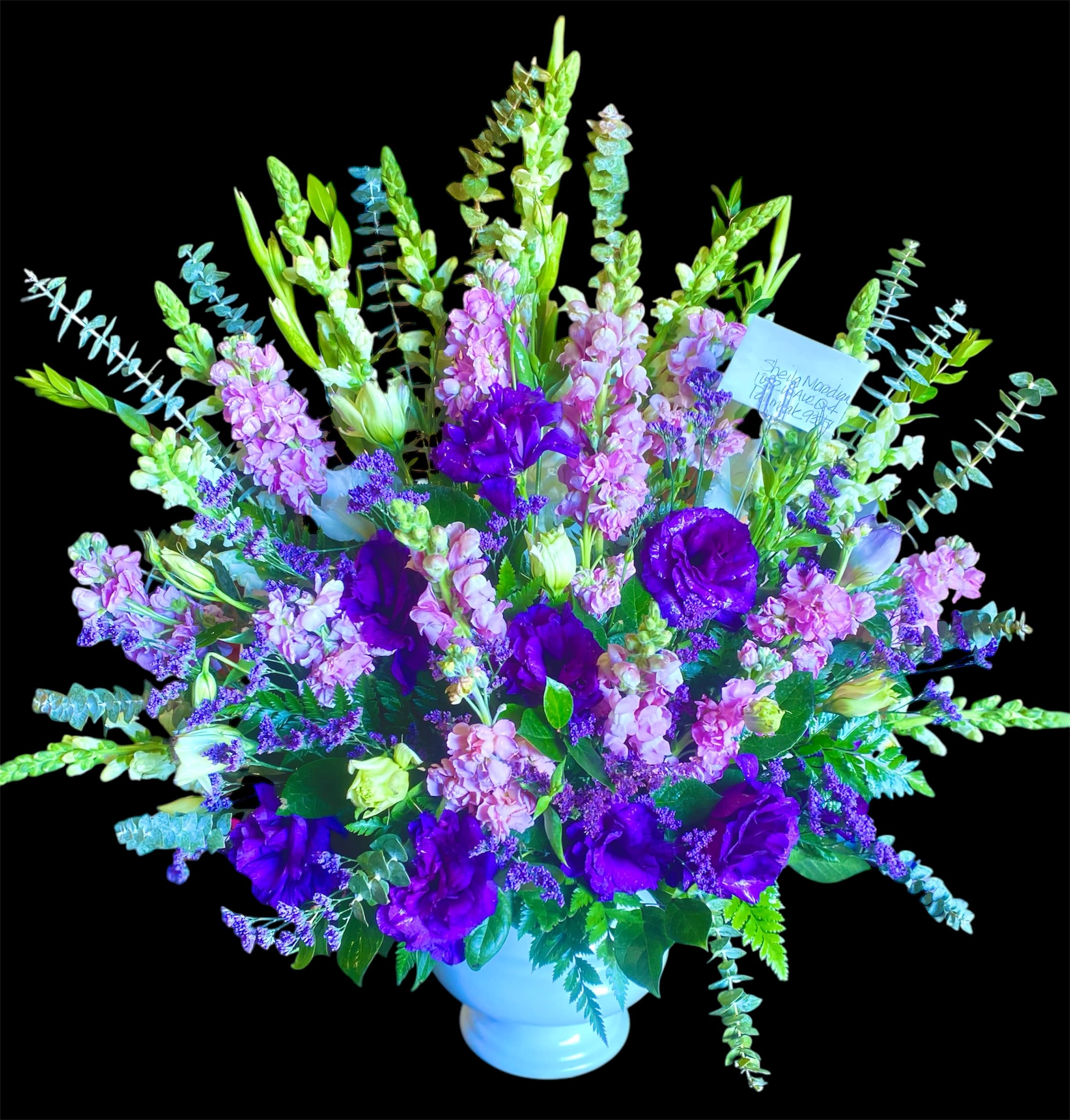 Purple and pink floral arrangement in a white vase